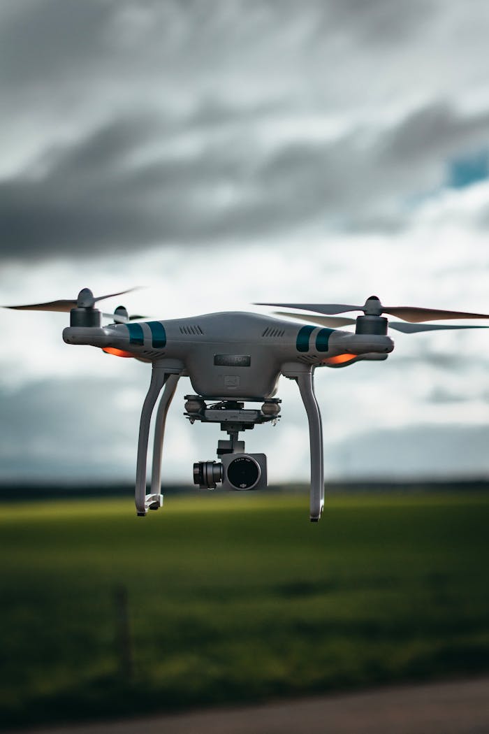 A drone flying over a green field under a dramatic cloudy sky, showcasing technology in nature.