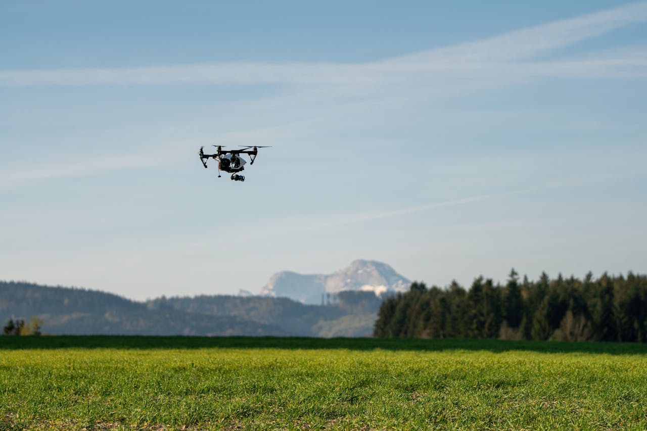 Drone flying over lush green farmland with mountain backdrop in Upper Austria.